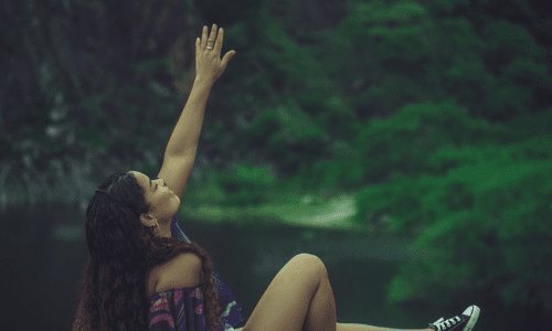 woman by water with left arm raised