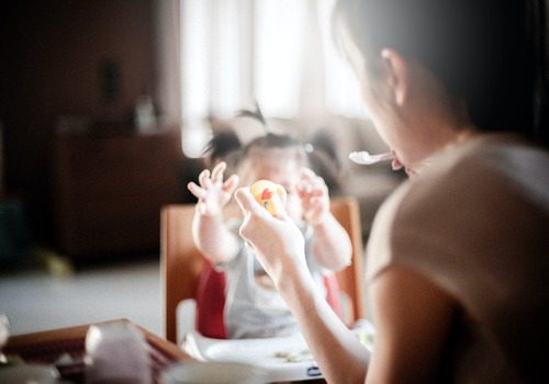mother feeding child in highchair
